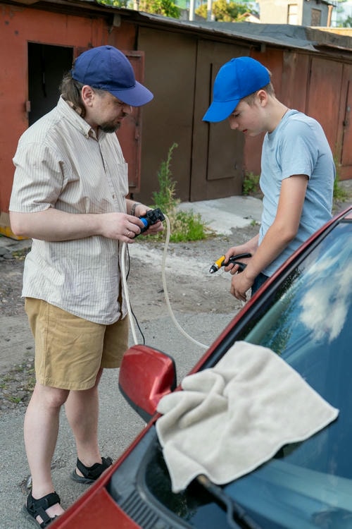 a mobile mechanic holding a hose to a man's car in austin
